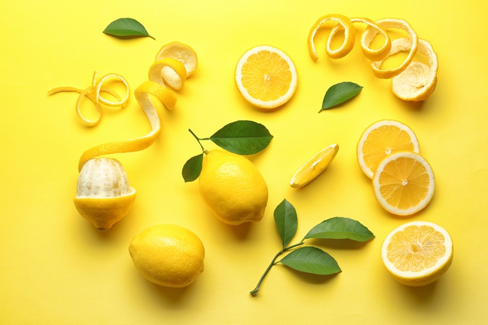 Delicious,sliced,and,peeled,lemons,with,green,leaves,on,color