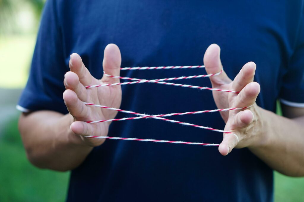 Closeup man hands is playing rope which called cats cradle game concept game involving the creation of various style figures between the fingers traditonal playing free photo